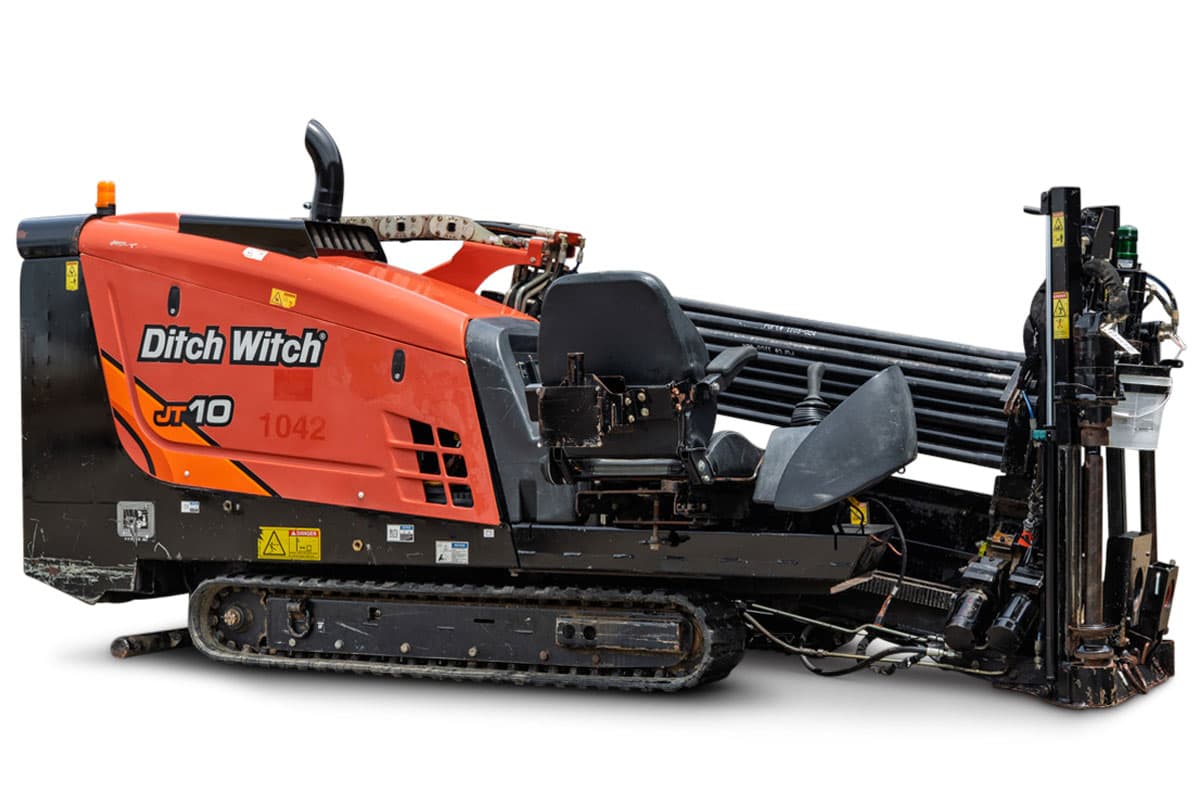 2018 Ditch Witch JT10 HDD rig, 3/4 view, orange hood, rubber tracks, operator seat, loaded drill pipe rack, carriage assembly visible