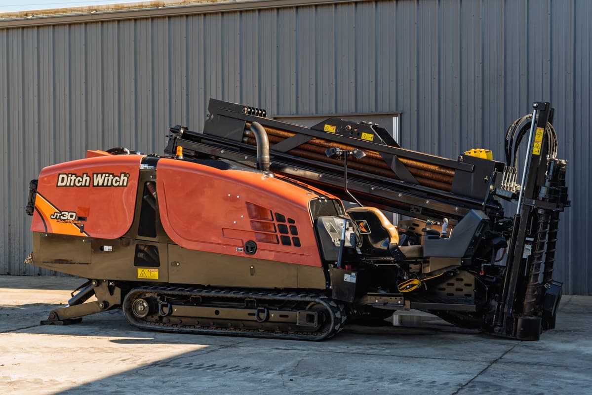 2016 Ditch Witch JT30 All Terrain HDD rig, side view, orange hood, rubber tracks, loaded drill pipe rack, operator station visible