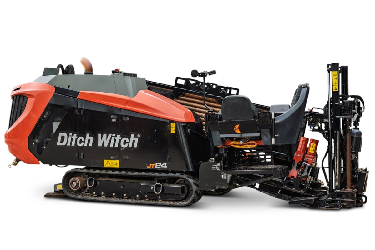 2024 Ditch Witch JT24 HDD drill, 3/4 right side view, rubber tracks, loaded drill pipe rack, operator seat, and exposed drill carriage visible.