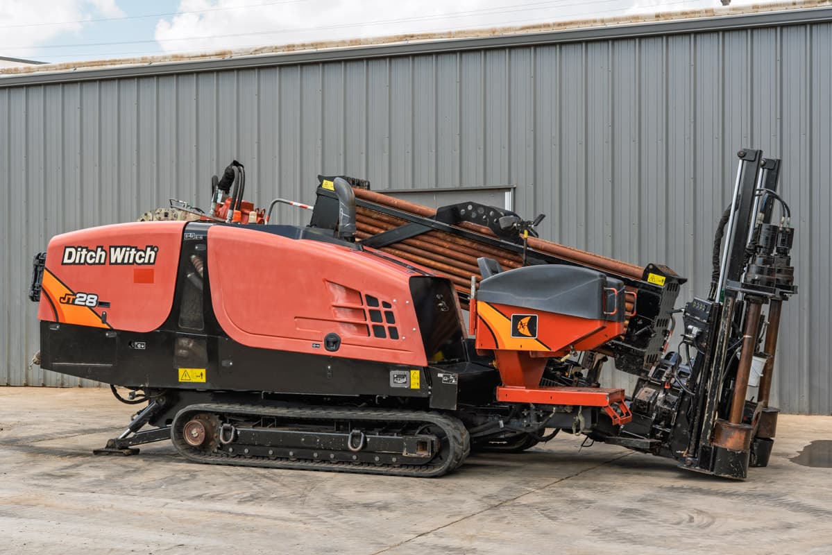 2021 Ditch Witch JT28 HDD drill, driver-side 3/4 view, rubber tracks, loaded drill pipe rack, angled carriage with vise assembly