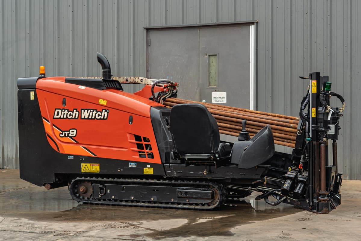 2016 Ditch Witch JT9 HDD drill, side profile, orange hood, rubber tracks, loaded drill pipe rack, carriage assembly visible