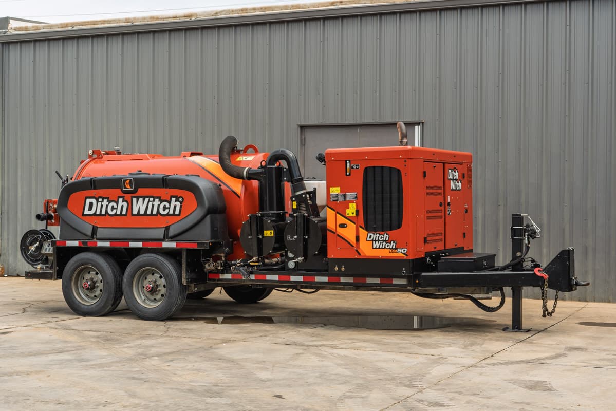 2023 Ditch Witch HX50 hydrovac trailer, driver-side 3/4 view, orange debris tank, vacuum hose, engine enclosure, tandem axle