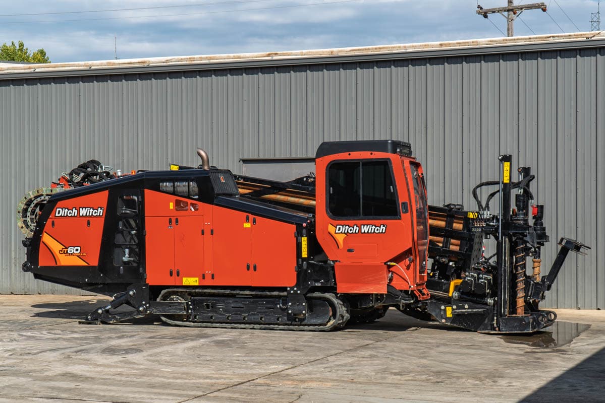 2025 Ditch Witch JT60 All Terrain HDD rig, full profile view, enclosed cab, loaded drill pipe rack, rubber tracks, anchor system