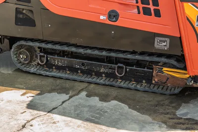 2017 Ditch Witch JT30 rubber track close-up showing track frame, drive sprocket, tie-down D-rings, and lower machine body panels