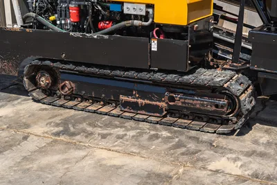 2020 Vermeer D24x40 S3 rubber track close-up showing worn tread, drive sprocket, idler, and engine compartment with hydraulic components above