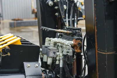2015 Ditch Witch JT20 hydraulic control valve bank with fittings, hose bundle, and manual lever, close-up detail view