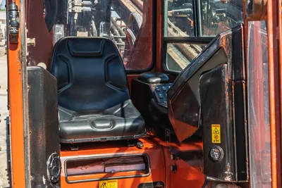 2014 Ditch Witch JT100 Mach 1 cab interior showing worn operator seat, joystick controls, open door, and drill pipe visible through rear window