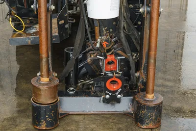 2015 Ditch Witch JT20 drill frame close-up showing pipe wrench vises, hydraulic hoses, anchor posts, and wear-used componentry.