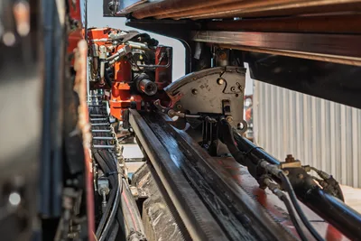 2022 Ditch Witch JT20 drill frame close-up showing rack-and-pinion thrust system, hydraulic hoses, carriage, and red engine components