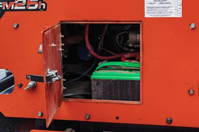 2015 Ditch Witch MR90 open access panel revealing battery, hydraulic hoses, and engine components on orange housing