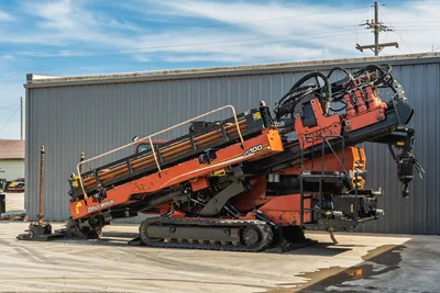 2014 Ditch Witch JT100 Mach 1 HDD rig, full side view, drill frame elevated, loaded pipe rack, rubber tracks, hydraulic components visible