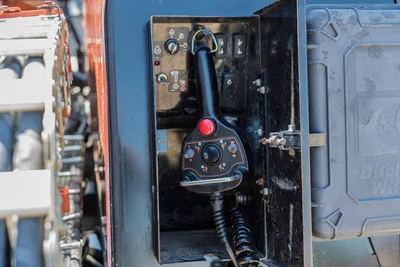 Ditch Witch JT20 remote control joystick station in open service compartment with mounted drill pipe rack background.