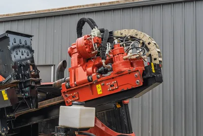 Ditch Witch AT40 rotary drive and carriage assembly with hydraulic hoses, rack-and-pinion drive, and heavy-duty cabling.