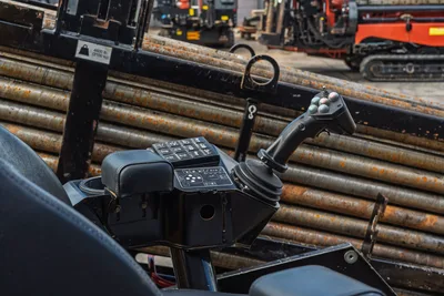 2018 Vermeer D24x40 S3 operator controls closeup showing joystick, function buttons, armrest, and drill pipe rack in background