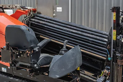 2018 Ditch Witch JT10 operator seat, joystick controls, and loaded drill pipe rack viewed from side angle