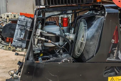 2021 Ditch Witch JT20 open engine compartment showing cooling fan, hydraulic reservoir, red fuel filter, hoses, and rubber track