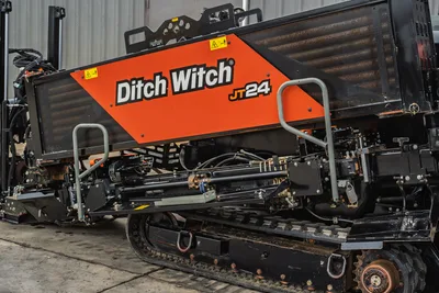 2024 Ditch Witch JT24 HDD drill side profile showing orange engine hood, drill frame, hydraulic components, and rubber tracks