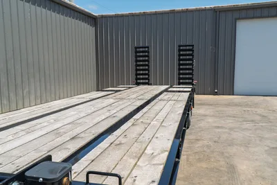 2026 Behnke FB8X30SDPT-40L flatbed trailer, wood deck surface, black steel frame, dual fold-down ramps, side angle view