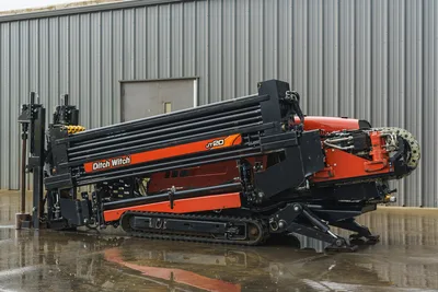 2015 Ditch Witch JT20 HDD drill, side angle, drill rack loaded with pipe, rubber tracks, vise, orange/black finish