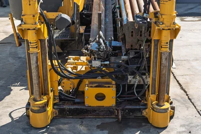 Rear view of Vermeer D36x50 Series II HDD rig carriage, vise assembly, hydraulic hoses, and drill pipe rack.