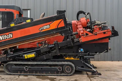 2016 Ditch Witch JT25 HDD drill, side view, elevated drill frame with spindle, loaded drill pipe, rubber tracks, and anchors visible