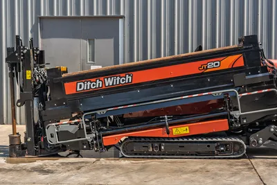 2022 Ditch Witch JT20 HDD drill, side view, angled drill frame elevated, rubber tracks, hydraulic components, drill pipe loaded, orange livery