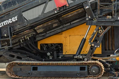 2017 Vermeer D100x140 S3 HDD drill close-up showing hydraulic hoses, drill frame, lift cylinder, steel tracks, and yellow body panels