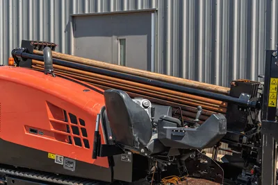 2022 Ditch Witch JT20 HDD operator station with joystick controls, orange hood, and loaded drill pipe rack overhead