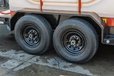 2023 MAXX-D C6X mud trailer tandem axle closeup showing Trailer King ST235/80R16 tires, black steel wheels, diamond-plate fender