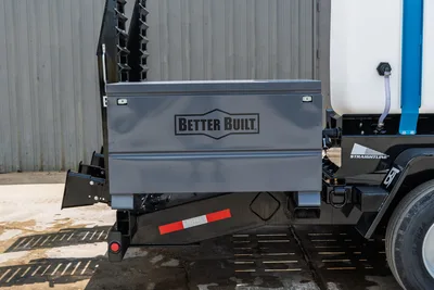 Behnke CBCT2324E-BT-R trailer rear closeup showing Better Built steel toolbox, white fluid tank, Straightline decal, and reflective DOT tape