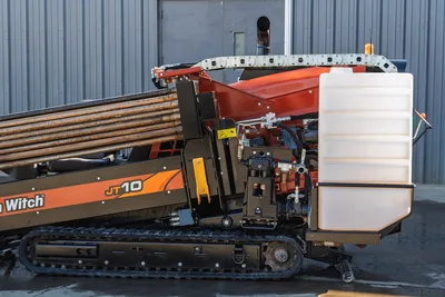 Ditch Witch JT10 HDD rig side view with drill pipe, rotary head, mud tank, tracked carrier, 9,000 lbs thrust