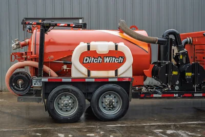 2021 Ditch Witch HX50 mud recycler, driver-side view, orange tank with branding, vacuum hoses, tandem axle trailer, pump system visible