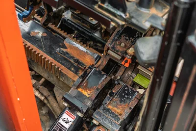 Close-up of Ditch Witch JT3020 rack and pinion assembly showing vice jaws, carriage rail, and maintenance condition.