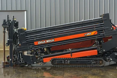 2015 Ditch Witch JT20 HDD drill, side view, loaded drill pipe rack, orange carriage, rubber tracks, vise assembly visible