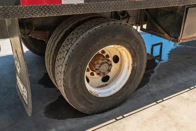 2015 International 7400 mud truck rear dual Hankook tire on rusted white steel wheel, diamond-plate frame rail visible above