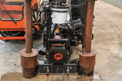 2016 Ditch Witch JT25 rear anchor assembly, vise, tie-down stakes, hydraulic lines, and drivetrain components, front-on view