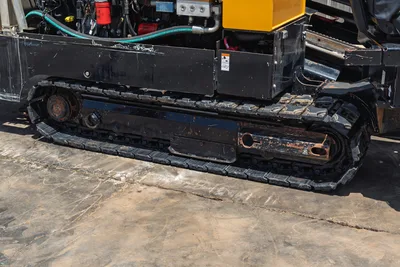 2021 Vermeer D24x40 S3 rubber track undercarriage, close-up side view, worn drive sprocket, hydraulic hoses visible above