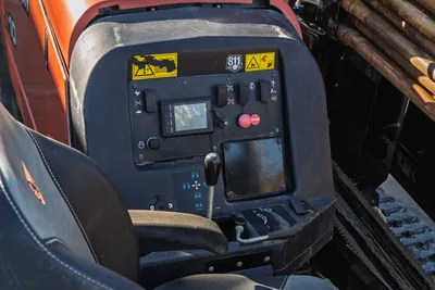 Ditch Witch JT10 operator cab interior, control panel with display screen, toggle switches, red emergency stop button, warning labels, 688 hours