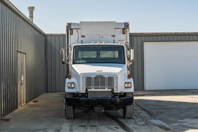Front view of 2000 Freightliner FL80 mud truck featuring white cab, chrome grille, and enclosed rear utility body.