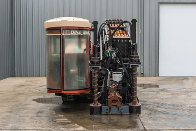 Front view of 2012 Ditch Witch JT3020 Mach 1 drill showing operator cab, pipe rack, hydraulic stabilizers, and drill chuck.