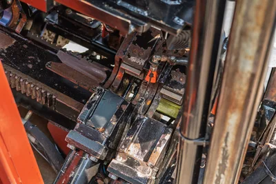 2017 Ditch Witch JT30 drill carriage and vise assembly closeup, showing worn pipe grips, rack gear, hydraulic components, heavy mud buildup