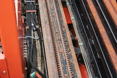 Top-down view of Ditch Witch JT4020 MACH 1 rack and pinion drive system, hydraulic lines, and drill pipe carriage.