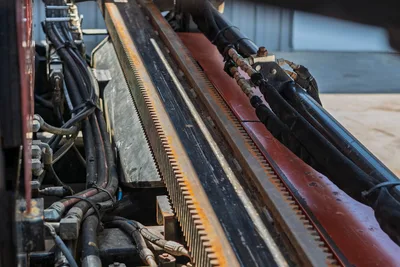 Close-up of Ditch Witch JT20 rack and pinion drill frame, hydraulic lines, and carriage assembly on the drilling rig.
