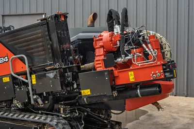 2024 Ditch Witch JT24 drill frame close-up showing red rotary drive, hydraulic system, carriage assembly, exhaust, and rubber tracks