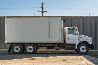 Side profile of white 2000 Freightliner FL80 mud truck with tandem rear axles and Morgan box body.