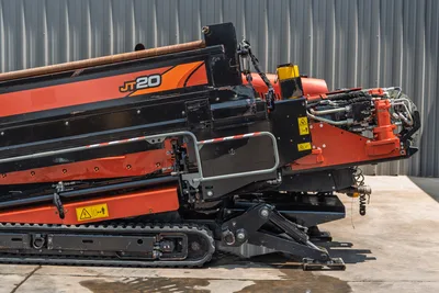 2023 Ditch Witch JT20 HDD drill, side angle showing drill carriage, hydraulic spindle, rubber tracks, anchor system, and loaded drill pipe.