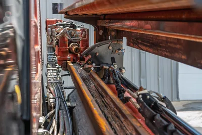 2023 Ditch Witch JT20 drill frame close-up showing rack-and-pinion thrust system, carriage, hydraulic lines, and drive motor assembly.
