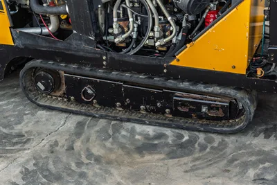 2016 Vermeer D23x30 S3 rubber track close-up showing hydraulic lines, fittings, and yellow frame with wear