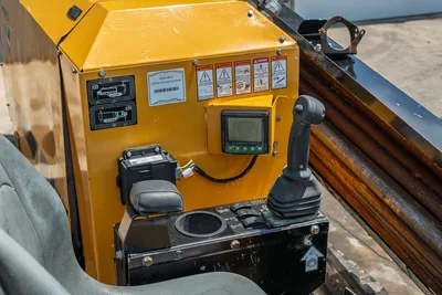 2021 Vermeer D8x12 operator control panel with LCD display, joystick, armrest, safety decals, and drill pipe visible alongside.