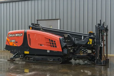 2015 Ditch Witch JT20 HDD drill, driver-side view, orange hood, rubber tracks, loaded drill pipe rack, pipe loader arm raised
